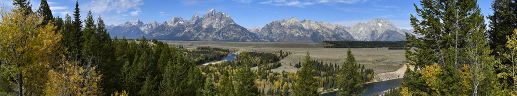 Wide view of the Grand Teton Mountain range from across a large landscape.